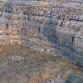 Steep Rock Cliff With Natural Textures And Sandy Ground Featuring Wooden Planks
