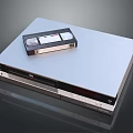 Silver VHS Video Recorder With Classic VHS Tape Placed On Top Surface