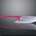 Decorative Red Handle Knife With Purple Pink Gradient Blade Circular Holes On Black Smooth Surface