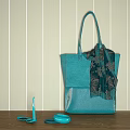 Turquoise Tote Bag With Decorative Scarf On Wooden Surface Against Striped Wall