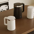 Three Modern Black And White Kettles Placed On Wooden Table With Stylish Design