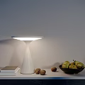 Modern White Table Lamp Glowing on Table with Books Walnuts and Bowl of Pears