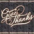 Illuminated Lighting Combination Featuring Handwritten Give Thanks Text and Glowing Frame on Black Stone Wall
