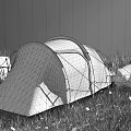 Yellow And Gray Camping Tent Set Up On Green Grassland With Mountain Rocks And Backpacks