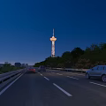 Illuminated Tower Beside Highway At Night With Trees And Moving Cars