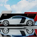 Silver Audi R8 Spyder on Display Platform with Red Black Design and Blue Sky Clouds