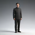 A Man Standing Full Length In Dark Colored Mao Suit Against Grey Background
