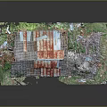 Dilapidated Barn Structure With Rusted Roof Collapsed Sections Surrounded By Overgrown Weeds And Debris