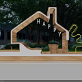 House Shaped Wooden Landscape Seat With HAPPY Lettering And Surrounding Green Trees