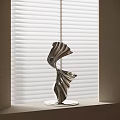 Abstract Silver Sculpture with Twisted Curved Design Metallic Finish on Windowsill Against White Blinds