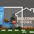 Floral Display Welcome Home Entrance Featuring White House Outline Flamingo Statues Green Plants And Flowers