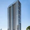 Modern High Rise Residential Building With Glass Windows And Balconies Against Clear Blue Sky