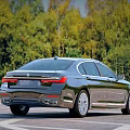 Black BMW 7 Series Luxury Sedan Parked Against Green Tree Background
