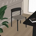 Modern Black Dining Chair With Woven Seat Next To Black Table And Green Plant