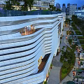Modern Commercial Complex With Wavy White Facade Rooftop Greenery Urban Outdoor Areas And Evening Lighting