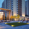 Vibrant Commercial Street Plaza With High Rise Buildings People Gathering Greenery And Evening Lighting