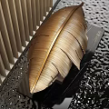Golden Feather Sculpture with Intricate Carving Details on Black Textured Surface