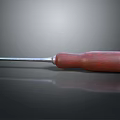 Screwdriver With Red Wooden Handle And Metal Shaft On Reflective Surface
