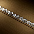 Elegant Metal Carved Decorative Strip With Scroll Patterns On Wooden Surface