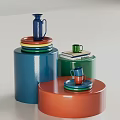 Vibrant Green Cup Beside Books With Blue Pitcher On Stacked Colorful Plates And Cylindrical Container
