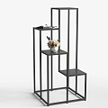 Modern Black Metal Shelving Unit With Multi Tier Varying Height Shelves And Small Potted Plant