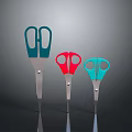 Three Different Colored Scissors with Metal Blades and Colored Handles on Dark Background