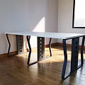 Modern Office Desk With White Top And Black Curved Legs On Wooden Floor In Sunlight