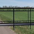Black Metal Garden Bench With Decorative Design Along Grass Path And Green Landscape