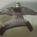 Man In Green Gray Jumpsuit And Helmet Skydiving In Mid Air Freefall Position