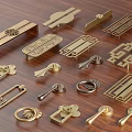 Golden Furniture Handles With Various Decorative Designs Displayed On Wooden Surface