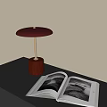 Red Base Metallic Stand Maroon Shade Table Lamp On Black Desk With Open Photo Book
