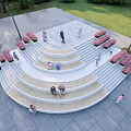 Circular Staircase with Red Benches People Resting Walking on Gray Stone Pavement by Grass Trees