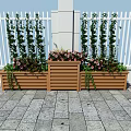 Decorative Garden Planters With Tall Green Plants Pink Flowers Against White Fence Stone Pavement