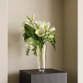 White Calla Lily Flowers In Transparent Glass Vase On Corner Table With Green Leaves