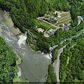 Scenic Natural Landscape with Flowing River Cascading Waterfalls and Lush Green Forest Surrounding Small Village