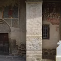 Ancient Building Wall With Detailed Figure Frescoes Archway Stone Column And Cross