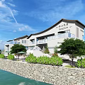 Modern Waterfront Guesthouse Building With Stone Wall Green Plants Trees Balconies And Scenic View