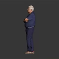 Senior Man in Blue Shirt and Blue Pants Standing With Arms Crossed Against Gray Background