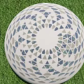Decorative White Sphere With Blue And Gray Triangular Patterns On Green Grass