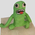 Green Plush Game Movie Character Sitting With Big Eyes Open Mouth And Teeth