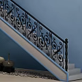 Ornate Staircase With Black Iron Railings Blue Wall Green Plant Black Vases And Pebble Decor