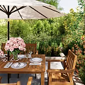 Outdoor Wooden Table and Chair Set with Pink Flowers Umbrella and Lush Greenery in Garden