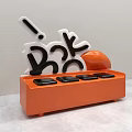Orange Vase With White And Black Letter Decorations And Round Floral Design