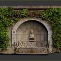 Ancient Stone Fountain Covered With Green Ivy Central Bust Statue And Metal Railings