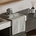 Folded Gray Towel on Bathroom Countertop with Aromatherapy Sticks and Decorative Bottles