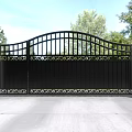 Wrought Iron Entrance Gate With White Pillars Spherical Top Decorations And Trees Blue Sky Background