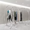 Modern Circular Display Rack With Metallic Frame Hanging Clothes And Mannequin Against Gray Wall