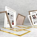 Stylish Photo Check-in Spot With Golden Frames Displaying Newspaper Content And Landscape Art On White Floor
