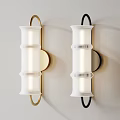 Two Wall Lamps With Gold And Black Frames White Cylindrical Shades Mounted On Light Wall
