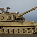 Sandy Colored Military Tank With Long Cannon And Top Mounted Equipment In Outdoor Setting
